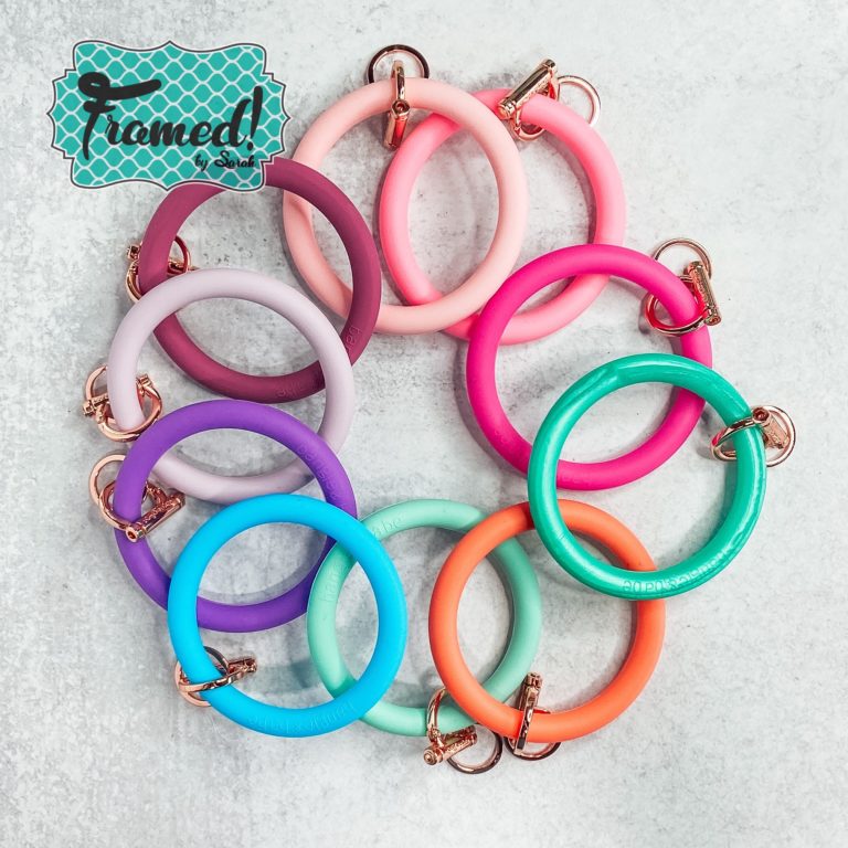 10 rubber keychain bracelets laid out in a rainbow of colors in a overlapping circle