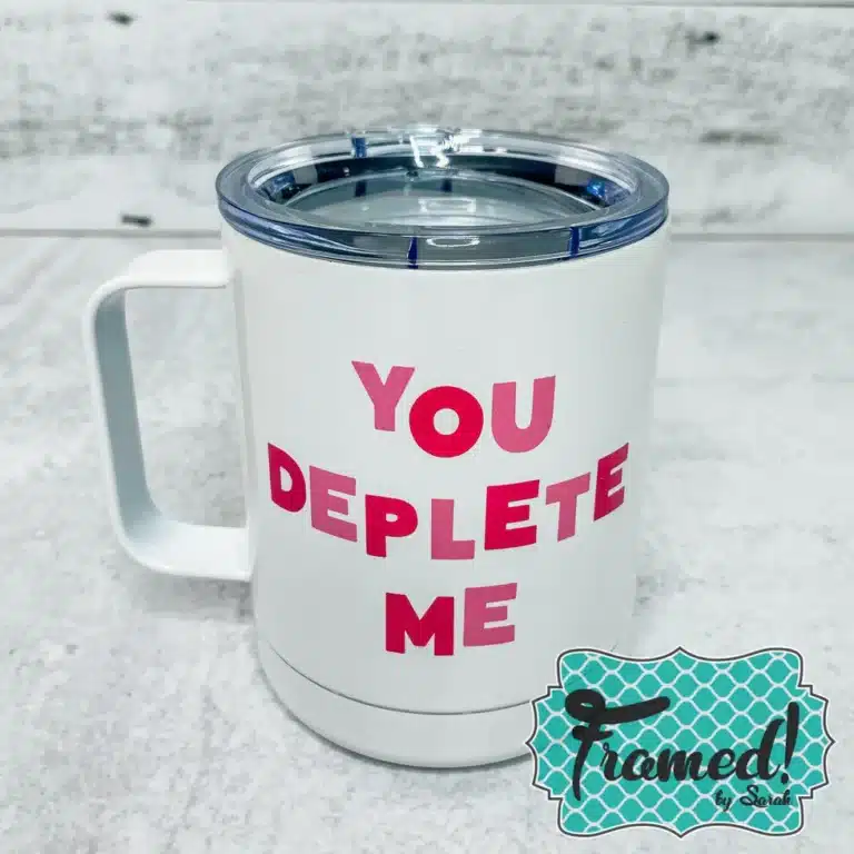 white travel mug with the words "you deplete me" in pink and red block lettering