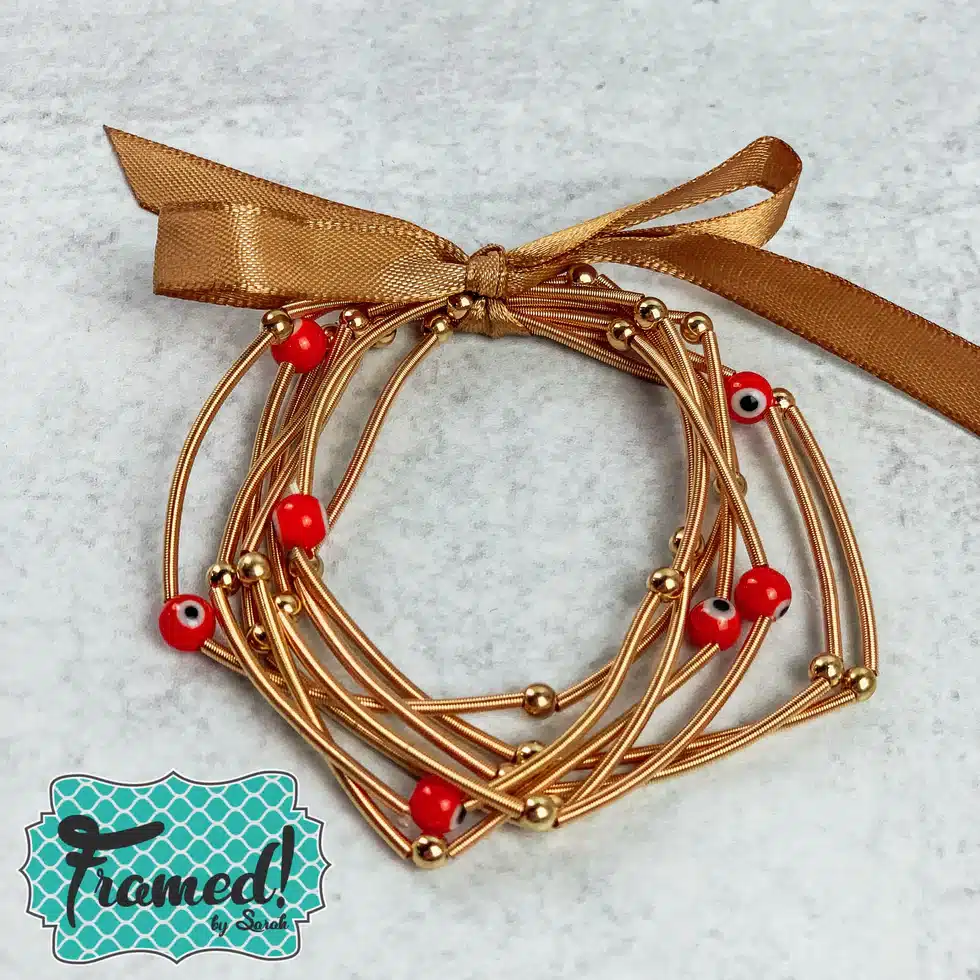 Multiple gold bracelets with red beads