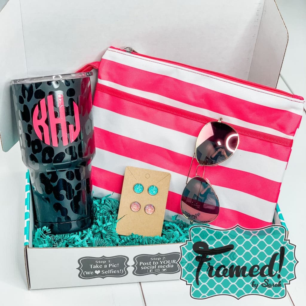 Gift box filled with a hot pink and white striped zipper pouch, sunglasses, earrings, and a monogrammed leopard print tumbler.