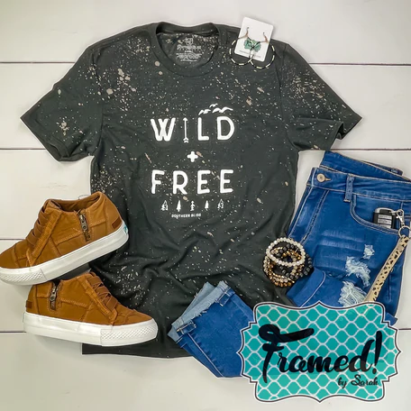 Charcoal "Wild + Free" bleached graphic tee styled with jeans, camel sneakers, and coordinating accessories.