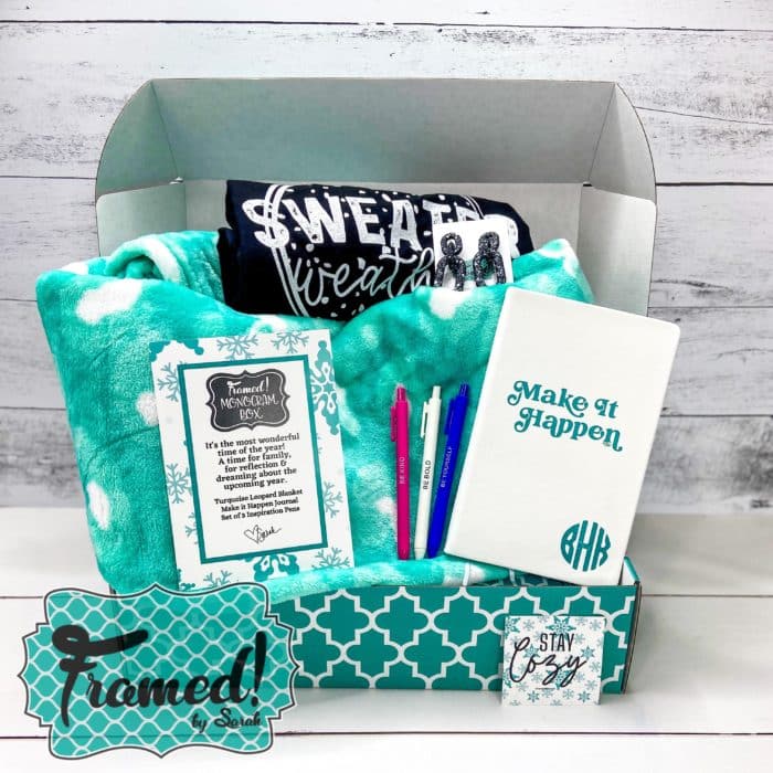 Monogram Subscription Box open with a teal blanket, Black tshirt, pens and notebook