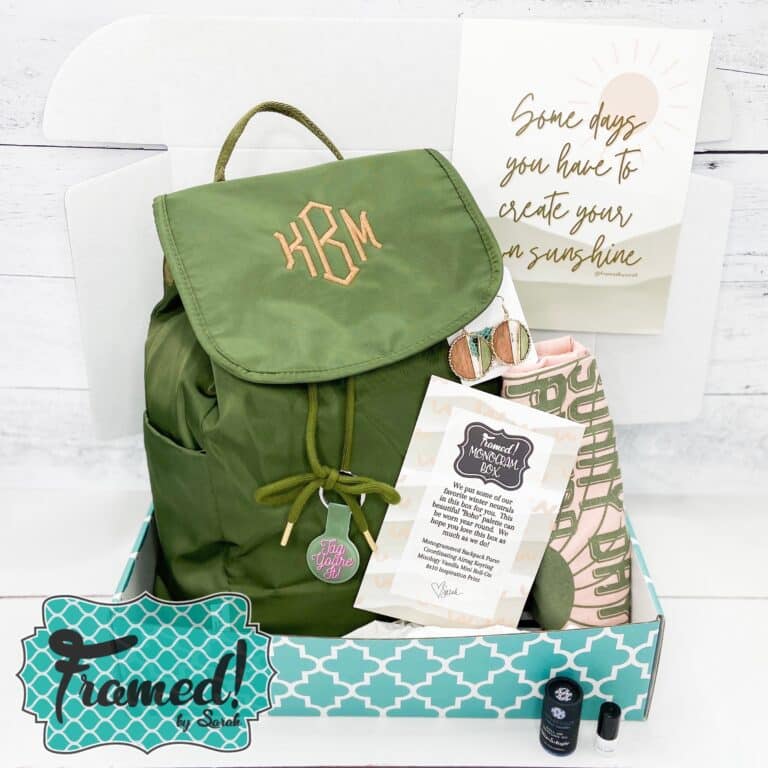 Monogram Box open displaying a green backpack with peach monogram, art print with quote, perfume, tshirt, and earrings.