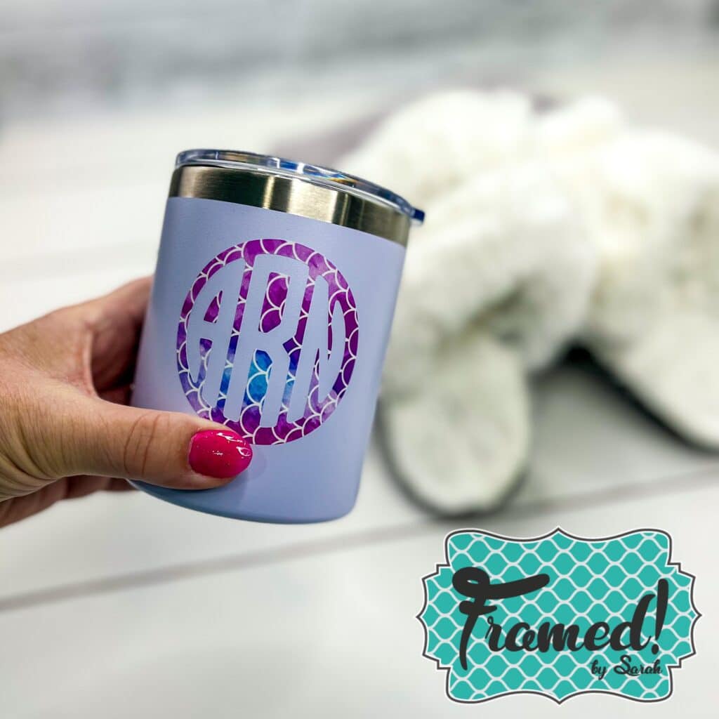 White tumbler with a pink monogram decal being held in from of fuzzy white slippers Framed by Sarah