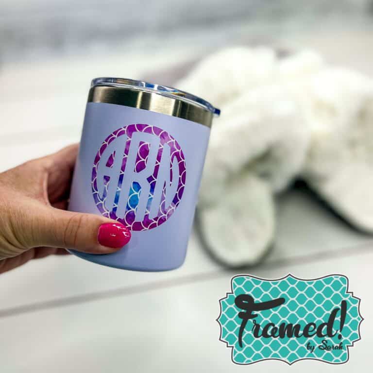 White tumbler with a pink monogram decal being held in from of fuzzy white slippers Framed by Sarah