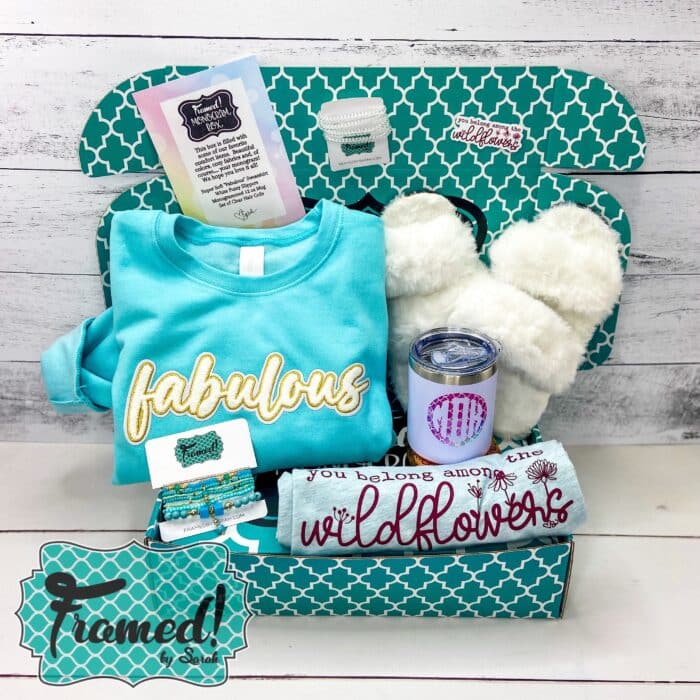 Teal colored box filled with a blue "fabulous" sweatshirt, white fluffy slippers, "wildflowers" tshirt, teal beaded bracelets, and a monogrammed tumbler