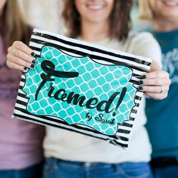 3 women blurred holding a black stripped bag with a turquoise Framed! label