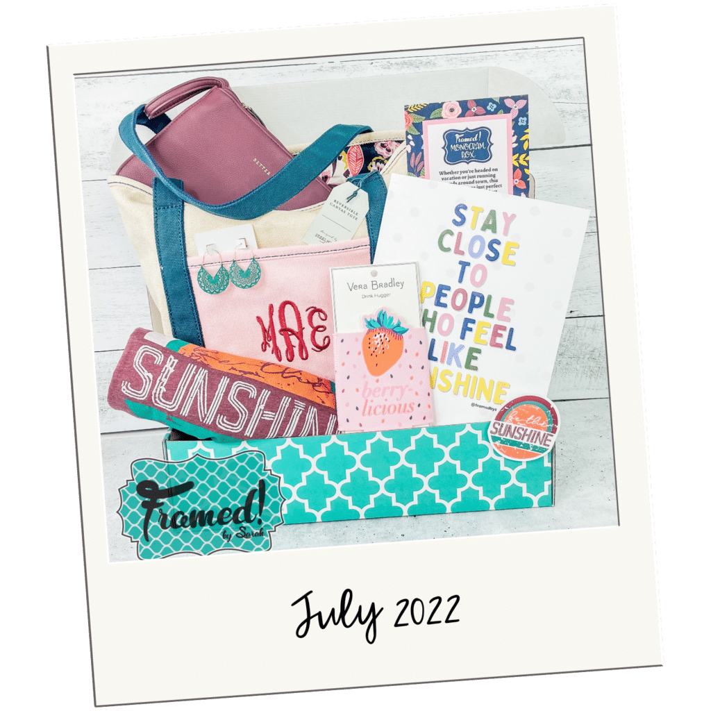 Polaroid picture of a Monogram Box open and displaying a Monogramed pink floral tote bag, a pink wristlet, "be the sunshine" tshirt, strawberry koozie, inspiration print, and accessories.