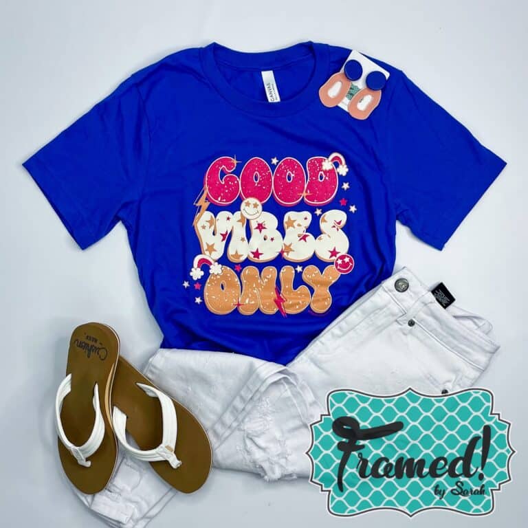 cobalt blue tshirt with pink, white and gold retro words "Good Vibes Only" styled with white jeans and sandals