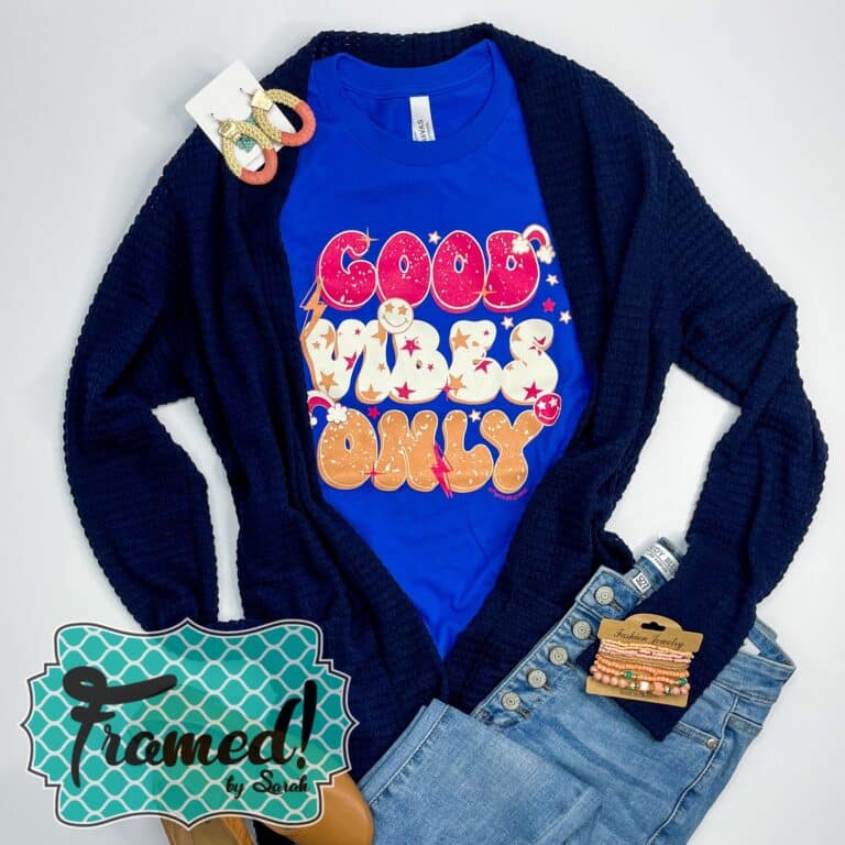 cobalt blue tshirt with pink, white and gold retro words "Good Vibes Only" styled with jeans and a navy cardigan