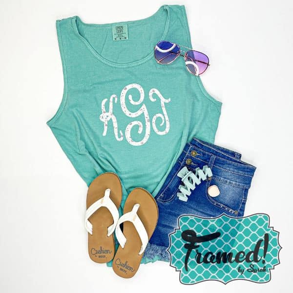 turquoise tank top with white monogram on the front styled with jean shorts, teal hairclip, white flip flop sandals, and sunglasses