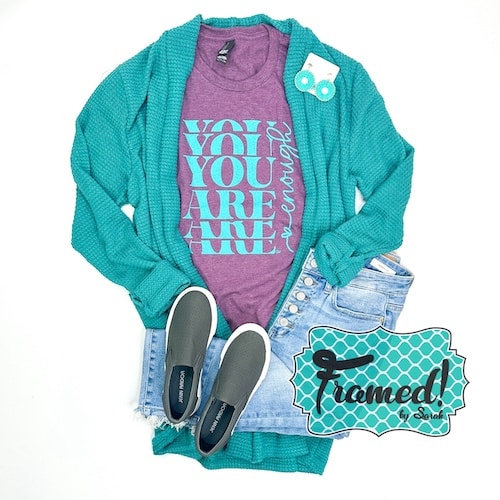 purple tee with "You Are Enough" written in teal styled with gray shoes, jeans, teal long cardigan and earrings