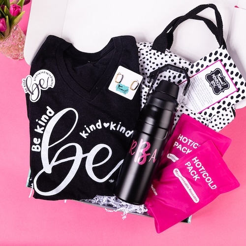 Framed Monogram Box open and displaying the April contents. Items include, Hot Cold Packs, Black waterbottle with hot pink monogram, white and black spot bag, earrings, black "Be Kind" shirt with a hot pink background