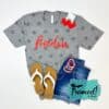 gray star tshirt with a red "freedom" across the chest styled with red earings, red white and blue beaded bracelets, cut off jean shorts, and white flip flop sandals