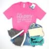 Hot pink "Being Happy Never Goes Out of Style" Lilly Pulitzer graphic t-shirt styled with gray wedge sneakers, ivory wristlet, high rise skinny jeans, turquoise earrings