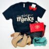 October T-shirt Club black Give Thanks shirt styled with monogrammed red wristlet, red earrings, jeans, and tan booties.