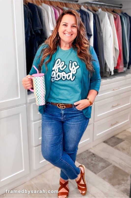 Sarah Williams wearing the blue Life Is Good tee styled with blue blazer, jeans, brown leather sandals, brown belt, and matching accessories