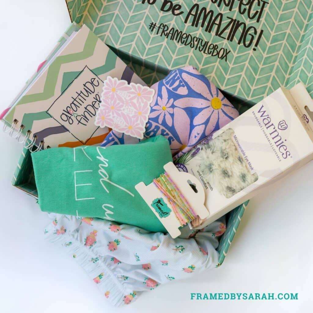 floral pajama shorts, teal t-shirt, blue t-shirt, eye mask, bracelet stack, and journal displayed in a teal subscription box