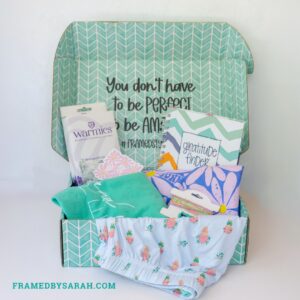 floral pajama shorts, teal t-shirt, blue t-shirt, eye mask, bracelet stack, and journal displayed in a teal subscription box