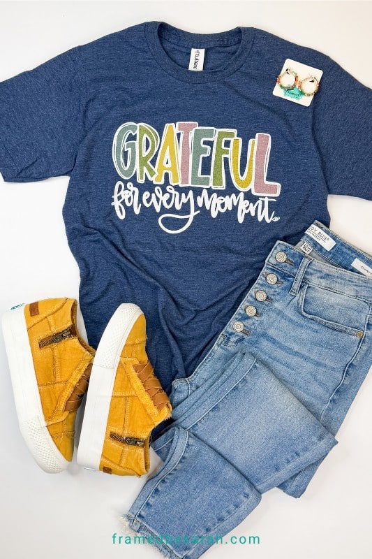 Flatlay photo of Navy "Grateful for Every Moment" t-shirt styled with jeans and ta sneakers