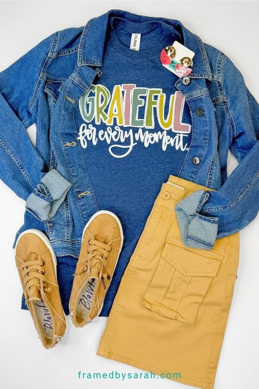 Flatlay photo of Navy "Grateful for Every Moment" t-shirt styled with skirt, sneakers, jean jacket